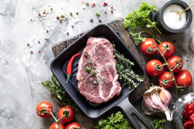 Çiğ taze et. Baharat, sebze ve otlar ile, bir ızgara tavada malzemelerle iki biftek. üst görünüm