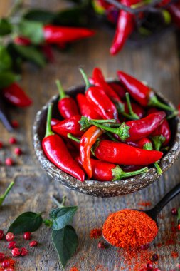 Ahşap bir arka plan üzerinde hasır metal sepet fesleğen bir sprig ile kırmızı biber.