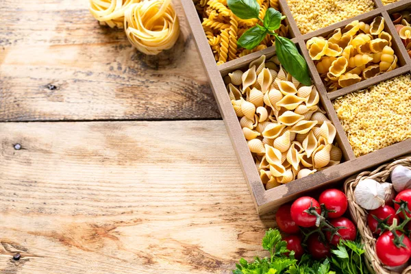 Different types of italian uncooked pasta in wooden box, whole wheat pasta, pasta, spaghetti, noodles, tagliatelle. Top view