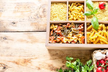 Tahta kutuda pişirilmemiş farklı İtalyan makarnaları, tam buğday makarnası, makarna, spagetti, erişte, tagliatelle. Üst görünüm.