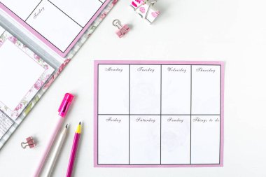 Pembe kırtasiyeli beyaz bir arkaplan üzerinde notlar ve yapılacaklar listesi olan planlayıcı.