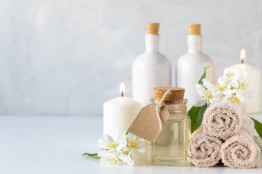 Yasemin yağı, mumlar ve havlular, beyaz arka planda çiçekler. Spa ve sağlık konsepti