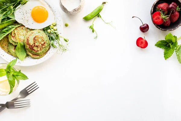 Gustosa colazione sana. Frittelle verdi con spinaci, uova e piselli verdi giovani. vista dall'alto. copia spazio — Foto Stock