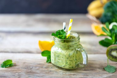 Ispanaklı, muzlu, portakallı ve cam kavanozda naneli ev yapımı yeşil smoothie. Detoks, diyet, sağlıklı, vejetaryen gıda konsepti