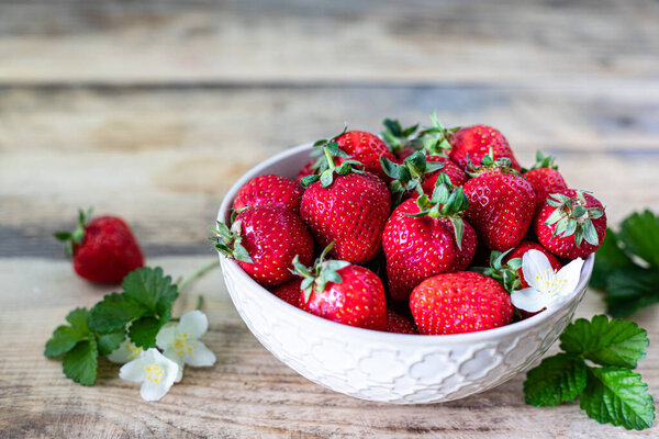 Bowl of strawberries on a wooden background.