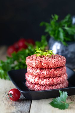 Dört çiğ hamburger pirzolası, tuzlu doğranmış et, otlar ve baharatlar ızgarada..