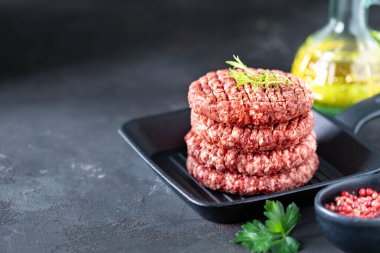 Dört çiğ hamburger pirzolası, tuzlu doğranmış et, otlar ve baharatlar ızgarada..