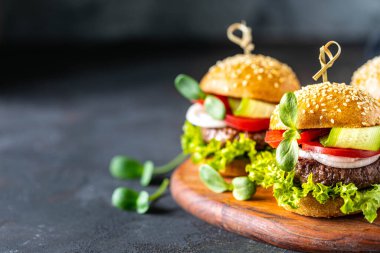 Köfteli hamburger, taze marul, domates, soğanlı siyah bir taş..