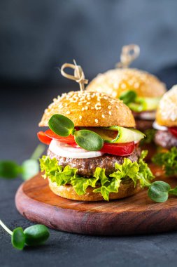 Köfteli hamburger, taze marul, domates, soğanlı siyah bir taş..