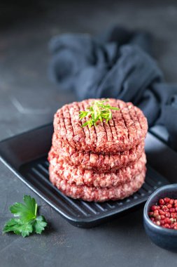 Dört çiğ hamburger pirzolası, tuzlu doğranmış et, otlar ve baharatlar ızgarada..