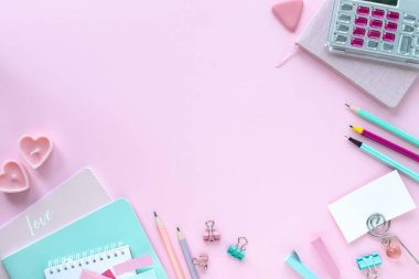 Okul ve ofis için kopyalanmış pembe zemin üzerine çeşitli renkli kırtasiye malzemesi