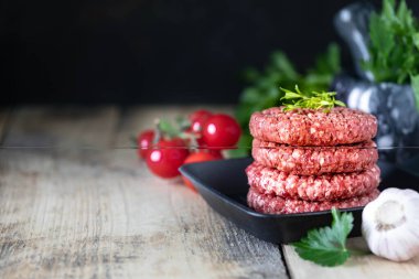 Dört çiğ hamburger pirzolası, tuzlu doğranmış et, otlar ve baharatlar ızgarada, kopyalama alanı.