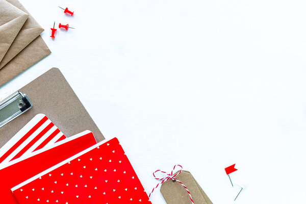 Notebooks and envelopes for school or office in red on a white table with copy space.