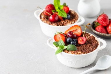 Beyaz arka planda çilek, kiraz ve nane ile süslenmiş güzel porsiyonlu bir İtalyan tiramisu tatlısı. Metnin için boşluk kopyala