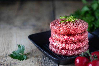 Dört çiğ hamburger pirzolası, tuzlu doğranmış et, otlar ve baharatlar ızgarada..