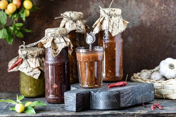 Három Üveg Válogatott Grúz Tkemali Szósz Hozzávalókkal Rusztikus Asztalon — Stock Fotó