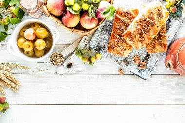 Elmayla pişirme, taze pişmiş elma ve beyaz ahşap bir masada puf böreklerden yapılan tarçın ruloları. Üst görünüm, kırsal biçim, boşluğu kopyala