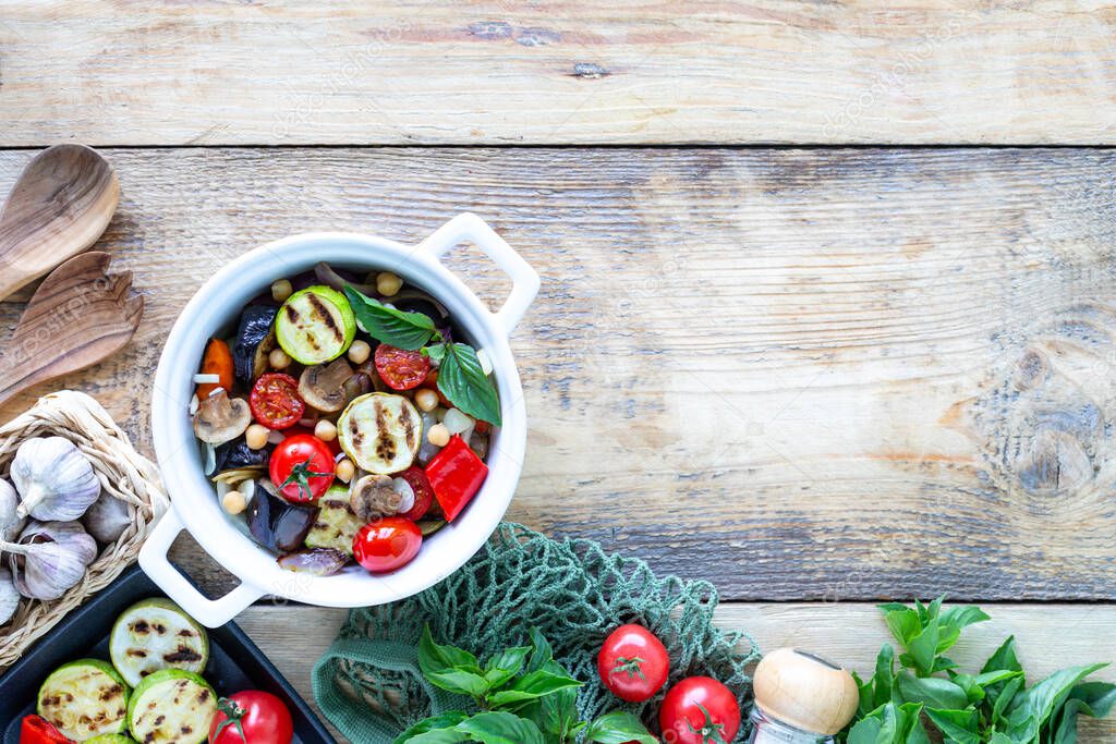 Grilled vegetables in a white ceramic pan with ingredients on a rustic background. Vegetarian food. Top view.