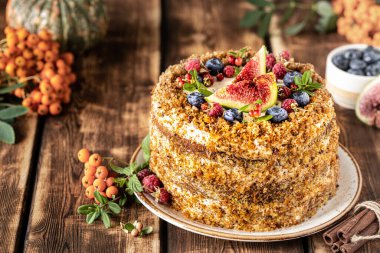 Ahşap arka planda böğürtlen ve incirle süslenmiş havuçlu kek. Geleneksel eşek hamur işleri.