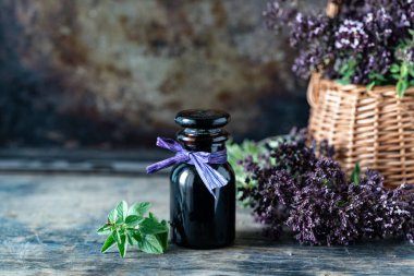 Tahta arka planda cam şişedeki Oregano yağı. Boşluğu kopyala