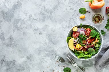 Beyaz taştan bir arka planda tabakta taze sebze salatası. Üst görünüm