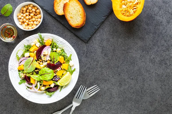 Insalata di verdure fresche con barbabietole, rucola, cipolle rosse, acetosa, ceci, zucca in un piatto bianco su fondo nero. Vista dall'alto — Foto Stock