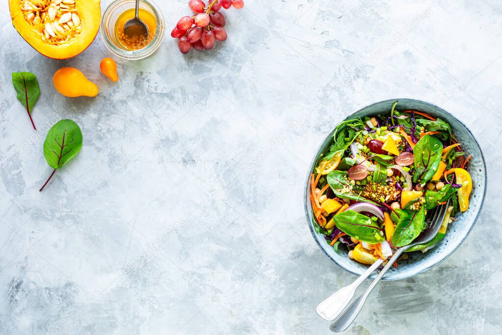 Fresh vegetable and pumpkin salad in a plate on a white stone background. Top view