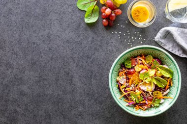 Taze sebze ve meyve salatası siyah taştan bir arka planda bir tabakta.