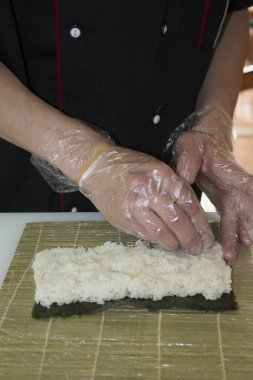 Ellerinizi kapayın ve suşi için pilavı öğütün bambu hasırında rulo yapın