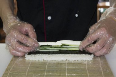 Şef bambu hasırında suşi yapıyor.