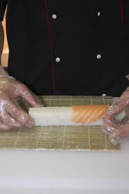 Şef bambu hasırlı somon suşisi yapıyor.