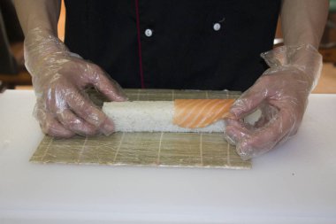 Şef bambu hasırlı somon suşisi yapıyor.