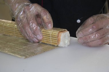 Erkek şef restoranda somonla suşi yapıyor. 