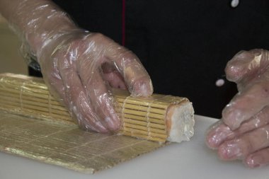 Erkek şef restoranda somonla suşi yapıyor. 