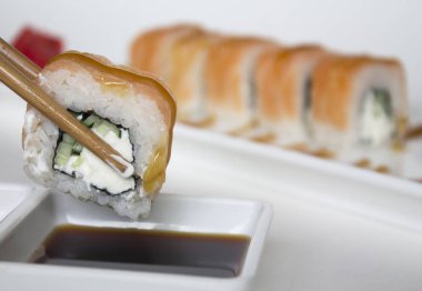 Yemek çubuklarıyla suşi alıp, yakınlaş. 