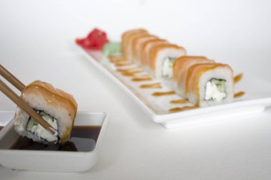 Yemek çubuklarıyla suşi alıp, yakınlaş. 