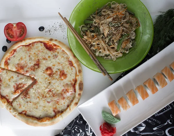 top view of pizza, rice noodles and sushi  on table