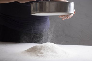 Fırıncı hamur hazırlıyor, süzgeçle un eleme yapıyor.