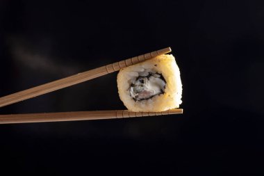 Yemek çubuklarıyla suşi alıp, yakınlaş. 