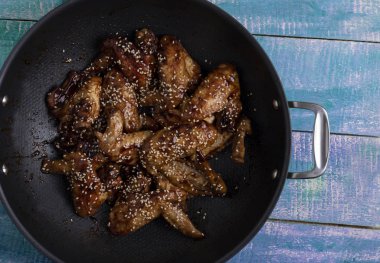 tatlı tuzlu tavuk kanadı üzerinde ahşap masa, susam ile kazan içine yakın çekim