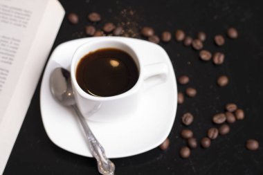  Masada bir fincan espresso, kitap ve kahve çekirdeği var.