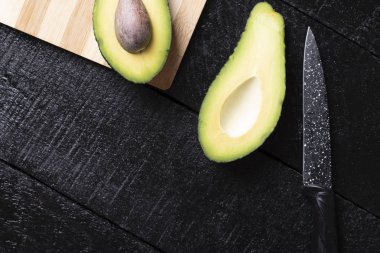 Tahtadaki avokado siyah arka planda izole edilmiş, sağlıklı besin maddeleri.