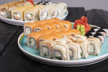 Masadaki mavi tabakta taze suşi ruloları var. 