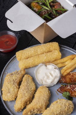 Fast food, balık, tavuk, peynir ve soslu patates kızartması. 