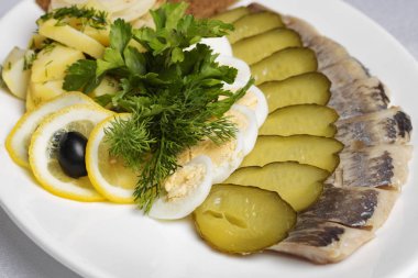 Yumurta, salatalık, limon, patates, ekmek, ringa balığı, maydanoz, dereotlu tabak manzarası.