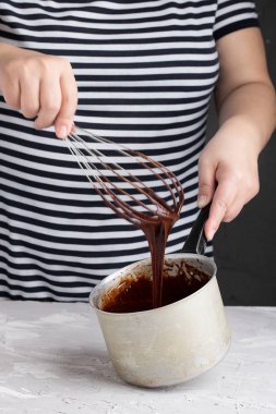 Kadın çırpıcıyı tutuyor, çikolatalı kremayı kaseye karıştırıyor.