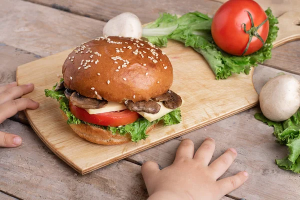 kızarmış mantar ve taze sebze, ahşap arka plan ile burger yakın çocuklar el