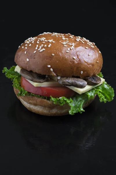 crispy mushroom burgers with marzipan cheese, tomato slice and salad leave, baked bun with sesame