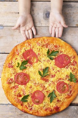 çocukların elleri gevrek bir pizza tutun, ahşap bir arka plan üzerinde, üstten görünümü