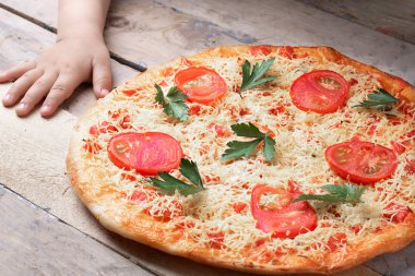 Margarita Pizza ile Çocuk elleri domates ve gri masa üzerinde iki kırmızı biber, üst görünüm ve metin için yer